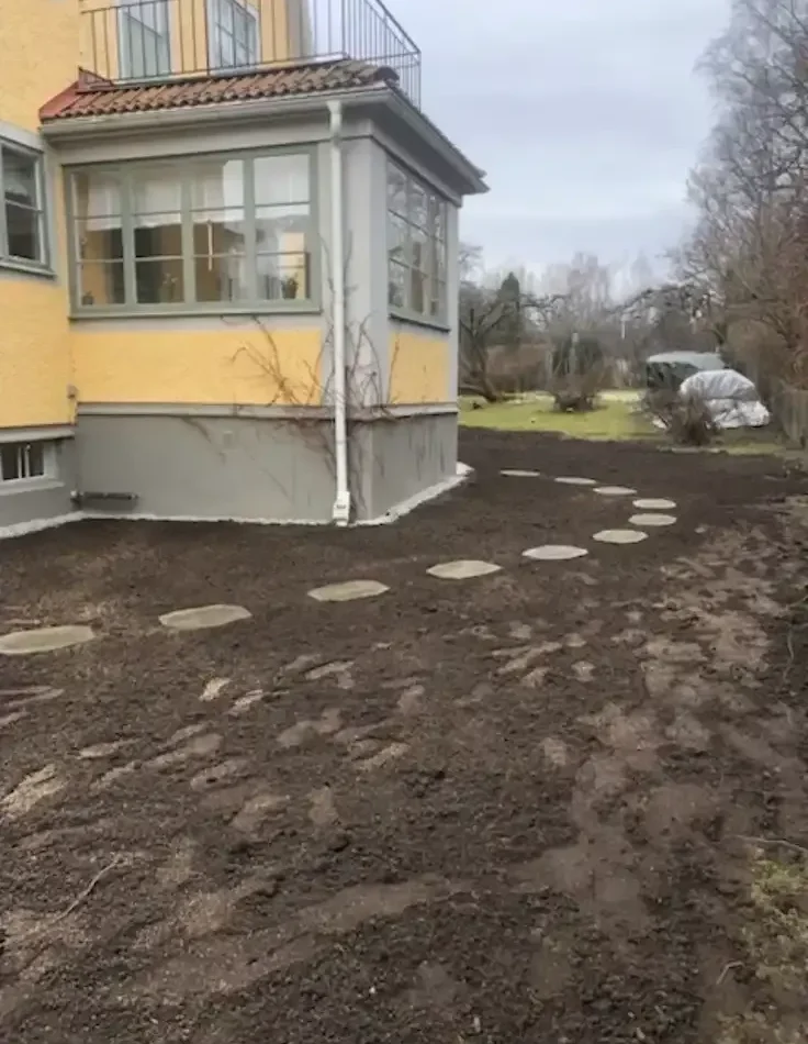 Finplanering med stensatt gångväg genom nyanlagd jord vid villa